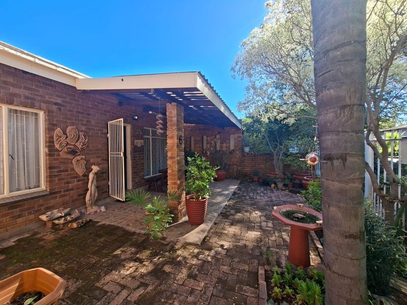 A private rear courtyard featuring a covered patio area, brick paving, and established garden elements, providing a quiet outdoor space.