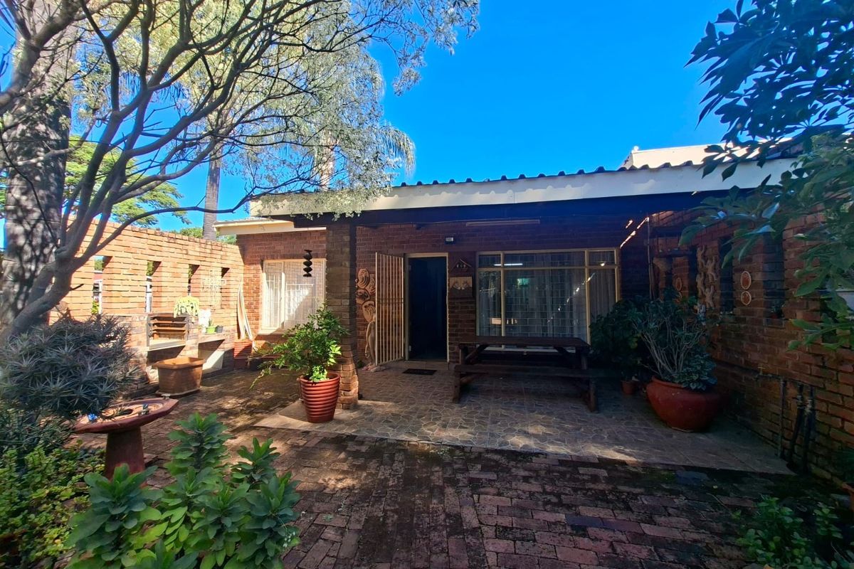 A private rear courtyard featuring a covered patio, brick paving, and a built-in brick braai area, perfect for outdoor entertaining.