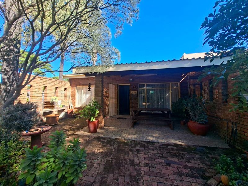 A private rear courtyard featuring a covered patio, brick paving, and a built-in brick braai area, perfect for outdoor entertaining.