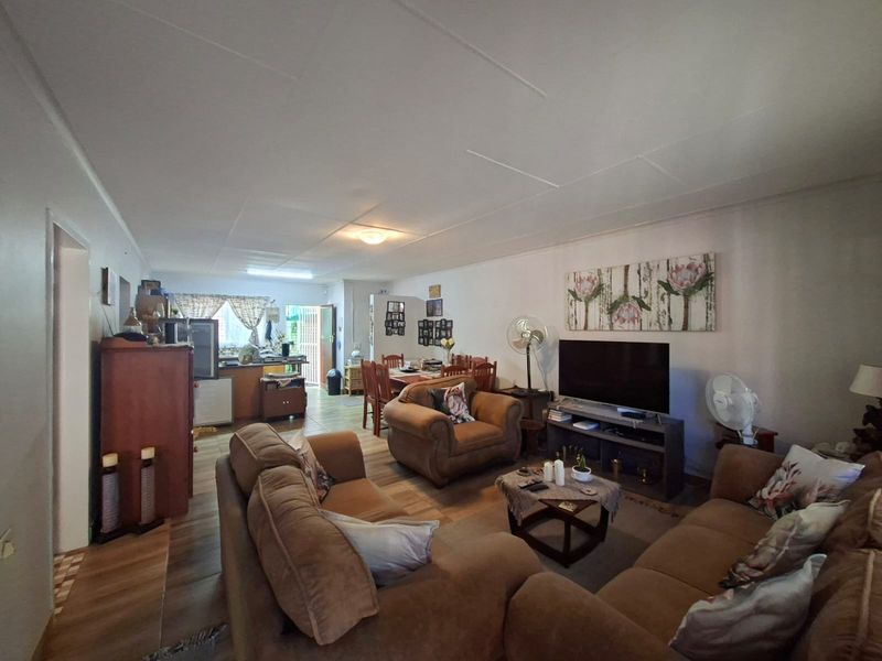 An open-plan living and dining area featuring tiled flooring and a connected kitchen space, providing a functional layout for daily living.