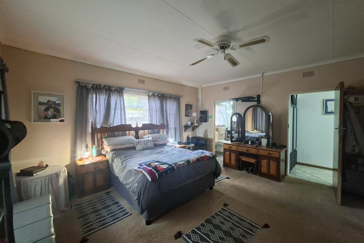 Spacious bedroom featuring a ceiling fan, carpeted flooring, and direct access to an en-suite bathroom.