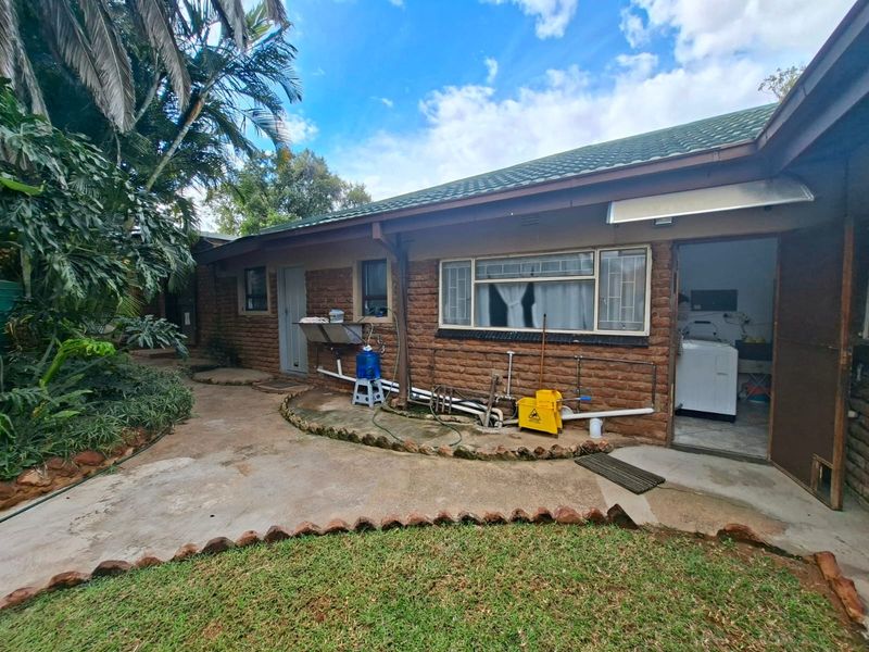 Rear view of the property featuring exposed brick walls, a tiled roof, and a concrete patio area with access to the laundry room.
