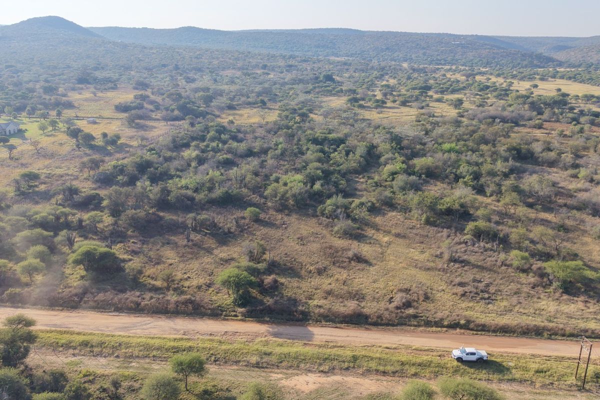 An aerial view of a large, undeveloped residential plot featuring native bushveld vegetation and access via a dirt road.