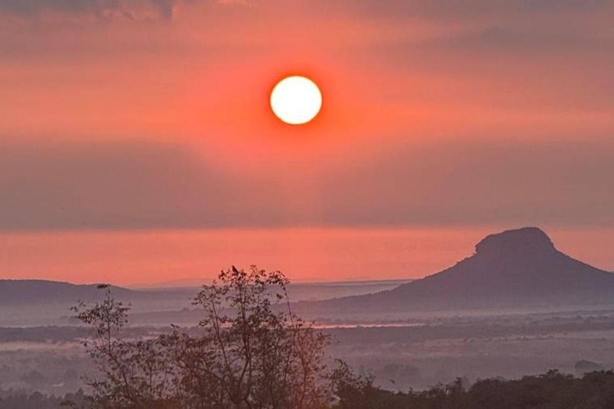 A scenic landscape view featuring a sunset over distant hills and natural terrain, highlighting the property's elevated position and surroundings.