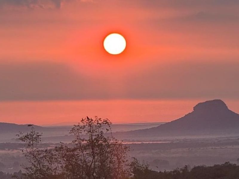A scenic landscape view featuring a sunset over distant hills and natural terrain, highlighting the property's elevated position and surroundings.