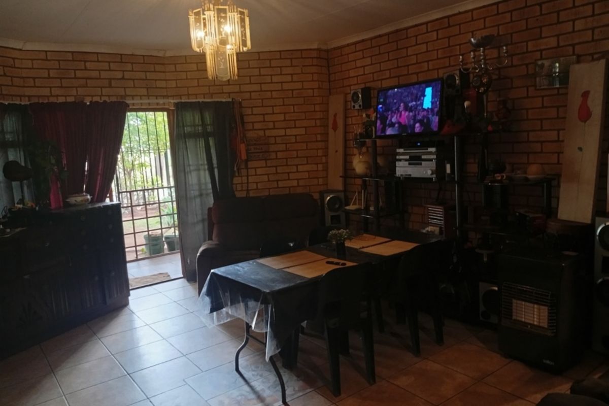 Living room featuring exposed brick walls, tiled flooring, and a decorative chandelier, with direct access to an outdoor area through a security gate.