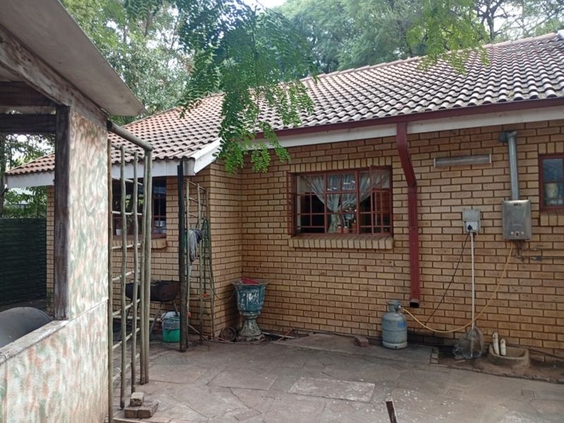 Rear exterior view of the house featuring a brick facade, tiled roof, and paved patio area with an installed gas geyser.