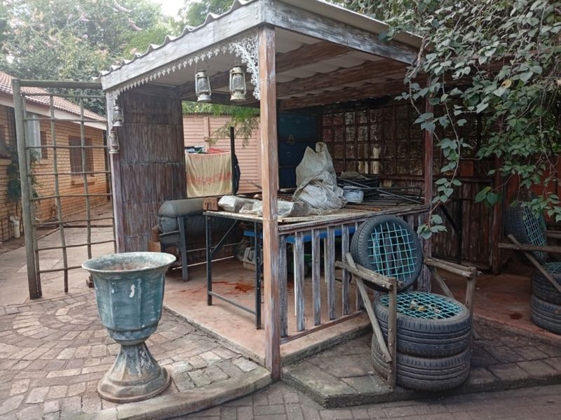 A weathered outdoor covered patio area featuring timber framing and paved flooring, requiring maintenance or renovation to improve its utility and aesthetic appeal.