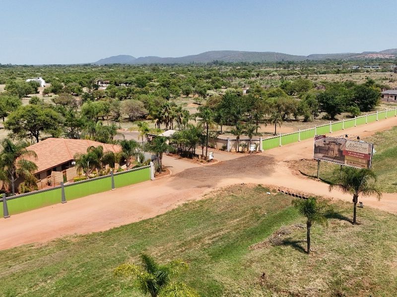 An aerial view of a residential land development featuring perimeter walls, dirt access roads, and surrounding natural landscape.