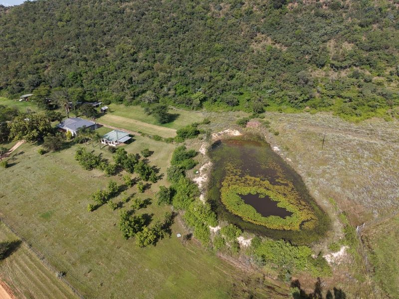 Aerial view of the farm property featuring a large dam, open grazing land, and the main dwelling with a metal roof.