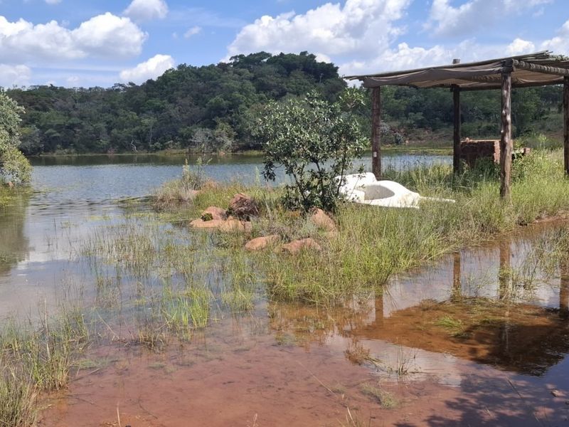 A scenic view of a natural dam on the farm property, featuring a rustic timber pergola structure near the water's edge.