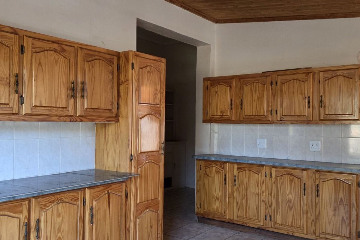 A functional kitchen featuring traditional wooden cabinetry, tiled backsplash, and durable tiled flooring, offering a classic aesthetic ready for modern updates.