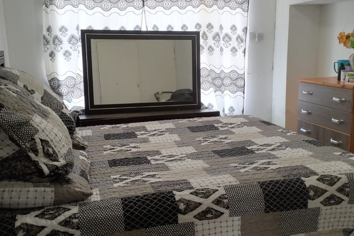 A standard bedroom featuring tiled flooring and a high-level wall air vent.