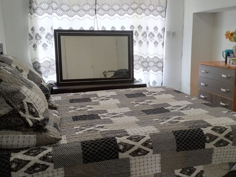 A standard bedroom featuring tiled flooring and a high-level wall air vent.
