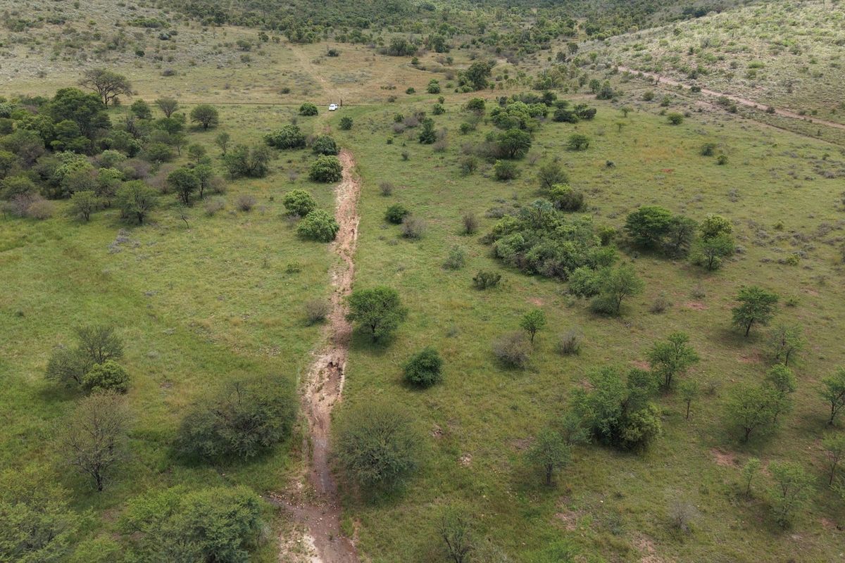 An aerial view of the expansive farm landscape featuring natural vegetation and a dirt access track winding through the property.