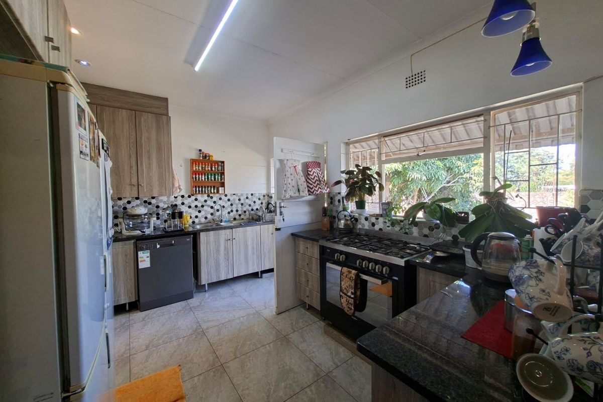 A functional kitchen featuring wood-look cabinetry, granite countertops, a gas stove, and a tiled backsplash with a view of the garden.