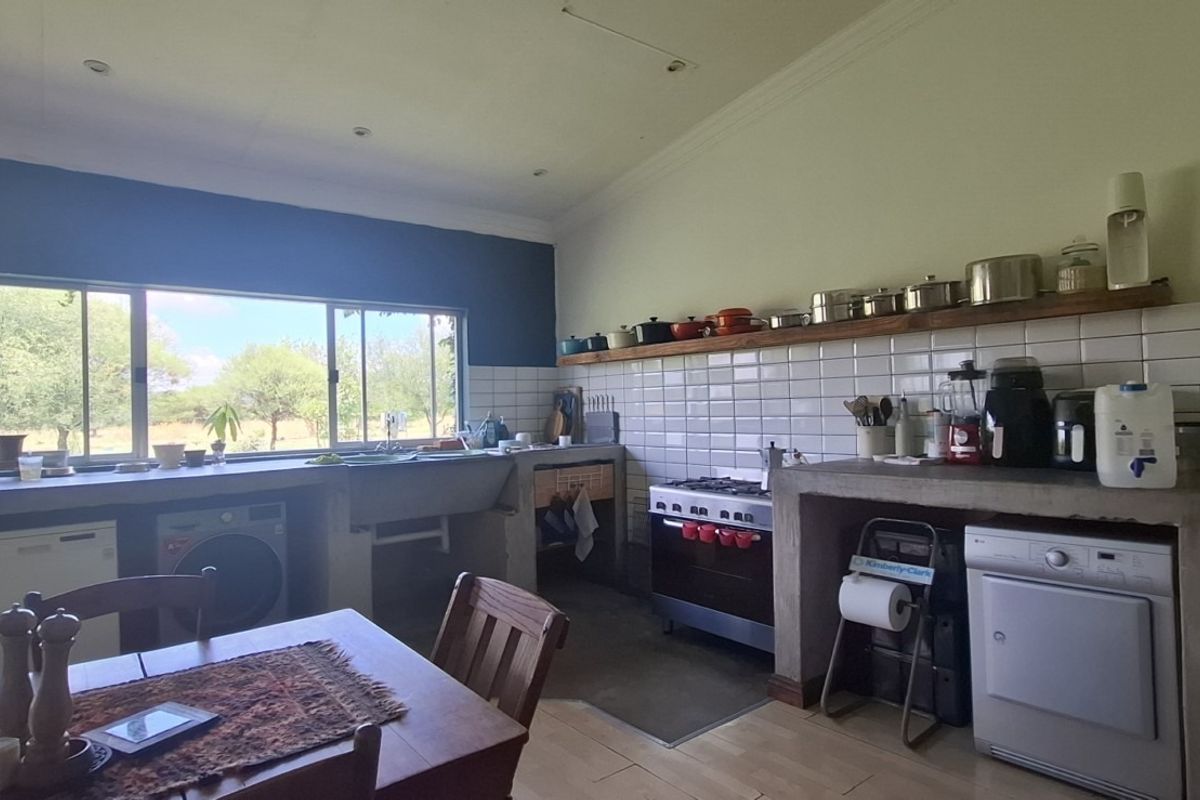 Spacious kitchen featuring concrete countertops, a farmhouse sink, gas stove, and white tiled backsplash with views of the surrounding landscape.