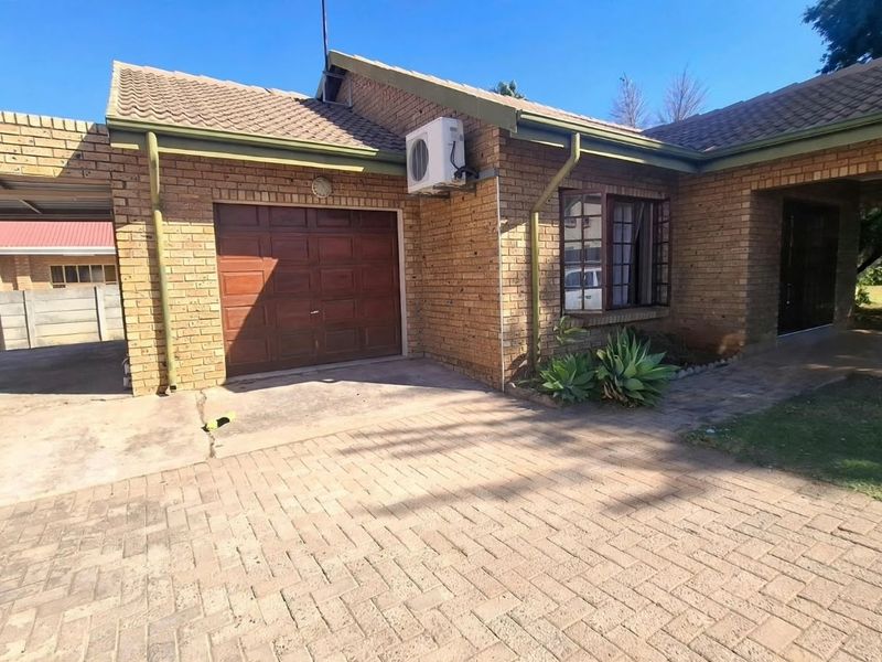 Front view of a face-brick house featuring a single garage, attached carport, paved driveway, and a covered entrance area.
