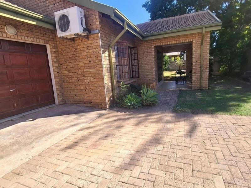 Front exterior view of a brick house featuring a paved driveway, single garage, and a covered entrance area.