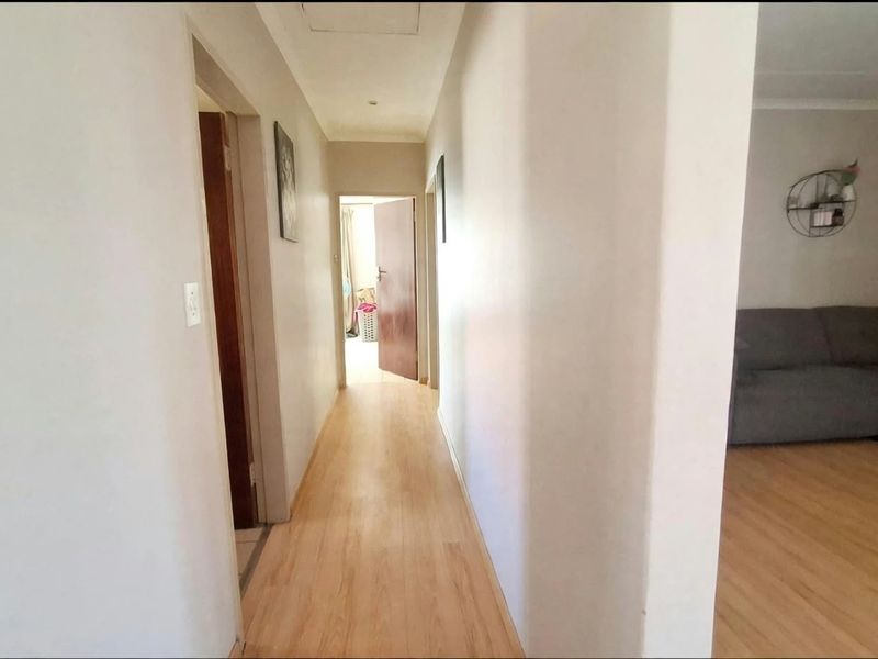 A functional hallway featuring light-toned laminate flooring, providing access to adjacent rooms and living areas.