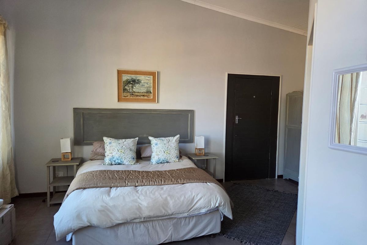 A bedroom featuring tiled flooring, a vaulted ceiling, and a solid core door, providing a functional and neutral sleeping space.