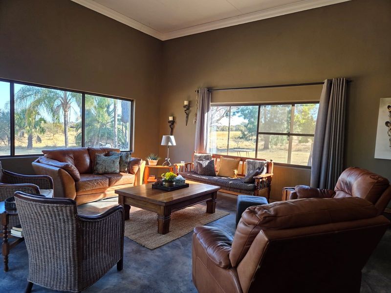 Spacious living room featuring polished concrete floors, high ceilings with crown molding, and large windows offering expansive views of the surrounding landscape.