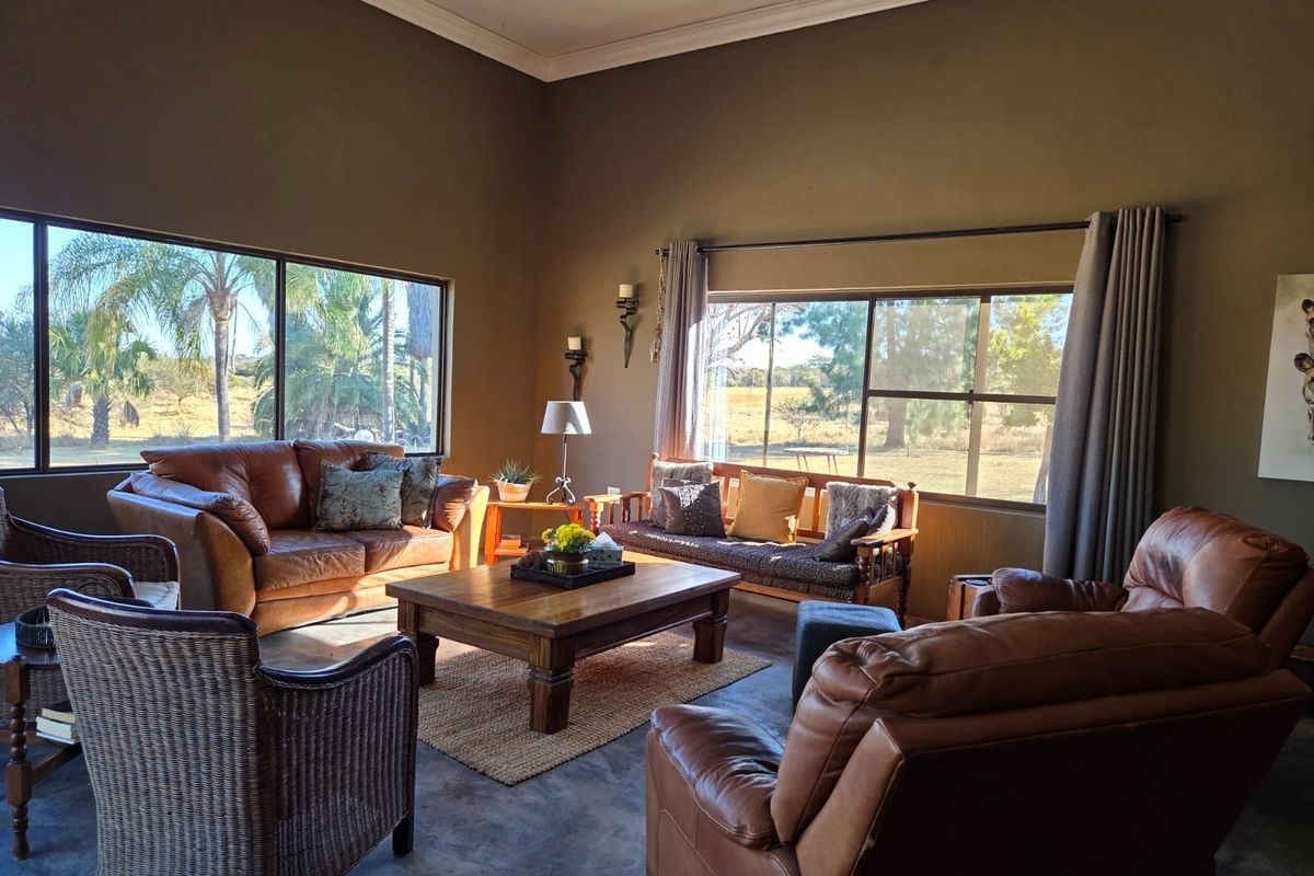 Spacious living room featuring polished concrete floors, high ceilings with crown molding, and large windows offering expansive views of the surrounding landscape.