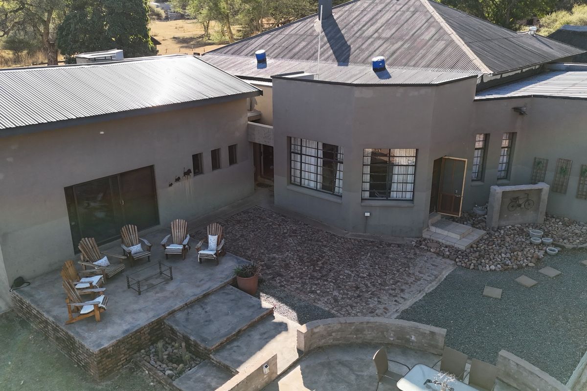 Aerial view of the lodge rear exterior, featuring a spacious concrete patio, stone-paved courtyard, and corrugated metal roofing.