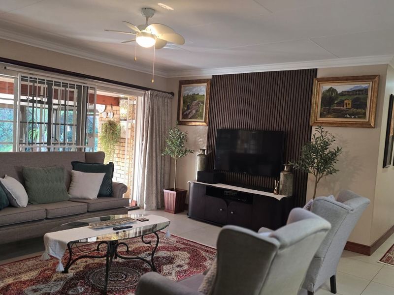 A comfortable living room featuring a slatted wood accent wall, tiled flooring, and a sliding glass door providing access to the patio.