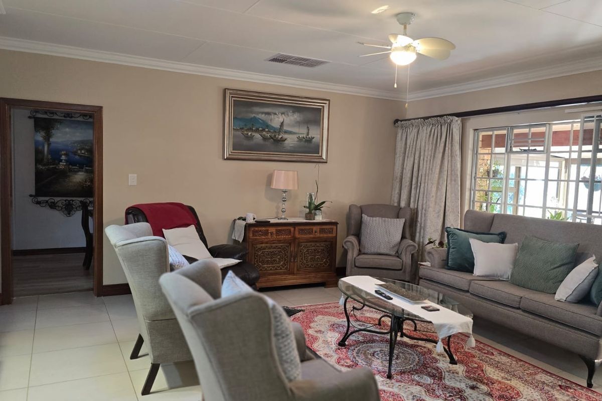 A comfortable living room featuring tiled flooring, coved cornicing, a ceiling fan, and a sliding glass door providing access to the outdoor area.