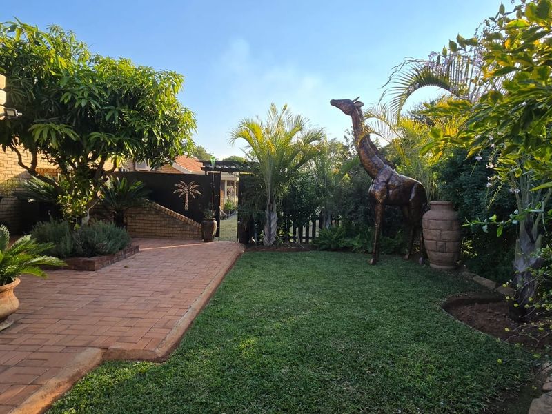 A well-maintained private garden featuring brick paving, lush landscaping, and a secure gated entrance.