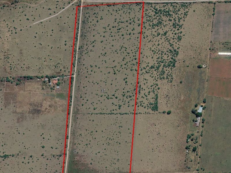Aerial view of a large, undeveloped residential plot of land with natural vegetation and clearly marked property boundaries.