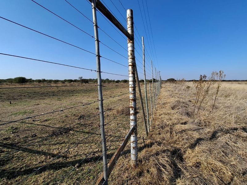 A view of the vacant land perimeter featuring wire fencing with visible signs of corrosion on the metal support posts.