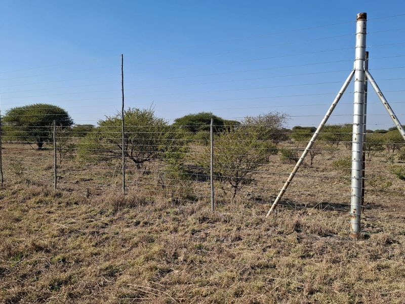 A view of the vacant residential land featuring wire perimeter fencing and metal support posts set against a natural bushveld landscape.
