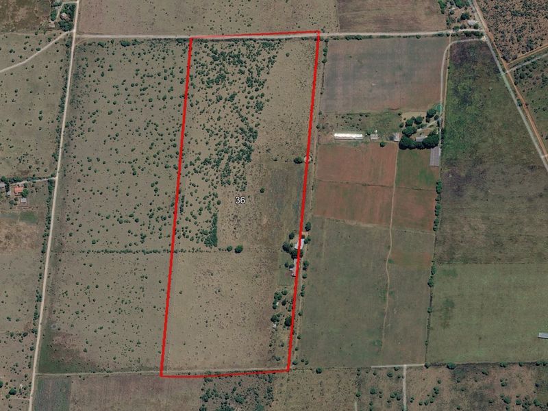 Aerial view of a large rural land parcel with boundary lines marked, showcasing the property's extent and surrounding landscape.