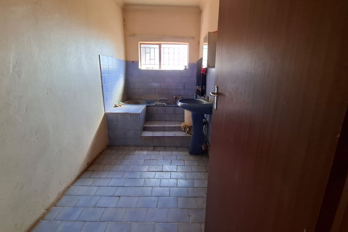 A dated bathroom featuring a built-in tiled bathtub and pedestal basin, requiring modernization and cosmetic updates to improve its overall condition and appeal.
