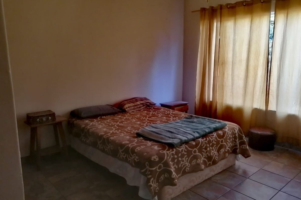 A bedroom featuring tiled flooring and natural light through window curtains.