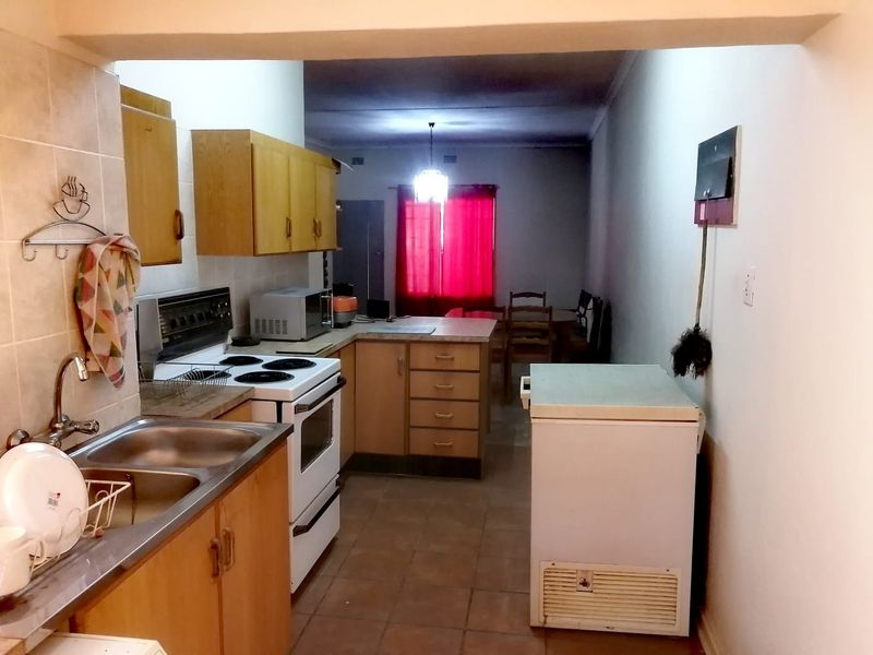 Open plan kitchen and dining area featuring dated laminate cabinetry, tiled flooring, and a functional electric stove setup.