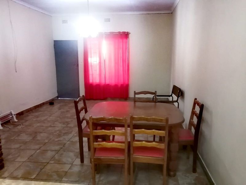 A simple dining area featuring ceramic floor tiles and a basic ceiling light fixture, providing a functional space for meals.