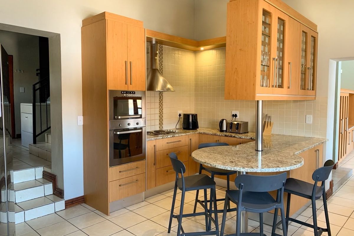 A functional kitchen featuring light wood cabinetry, granite countertops, a breakfast bar, built-in oven and microwave, and tiled flooring.