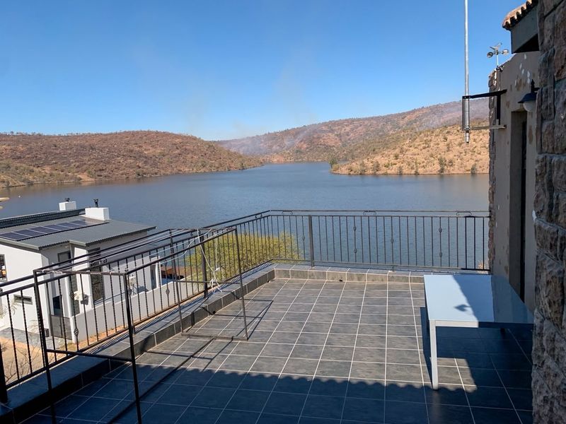 Spacious balcony featuring tiled flooring and metal balustrades, offering expansive views of the lake and surrounding landscape.