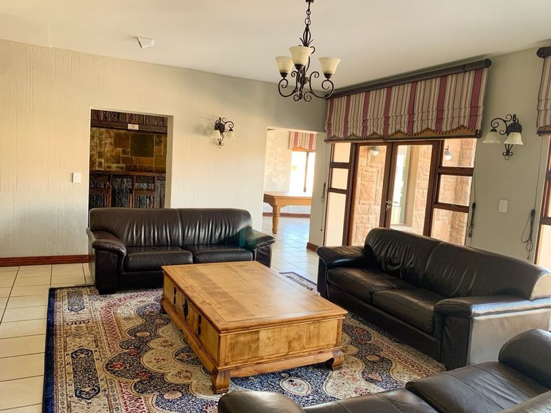 Spacious living room featuring tiled floors, stone wall accents, a built-in bar area, and large glass doors providing access to the outdoor space.