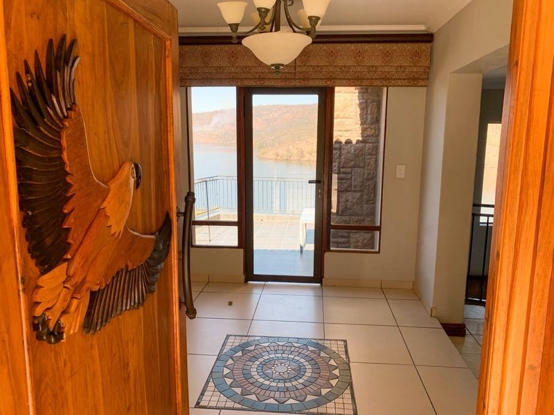 Welcoming entrance hall featuring tiled flooring with a decorative mosaic inlay, leading directly to a glass door with scenic water views.
