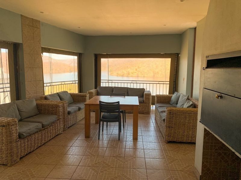 Spacious covered patio featuring a built-in braai, tiled flooring, and expansive views of the surrounding landscape, ideal for outdoor entertaining.