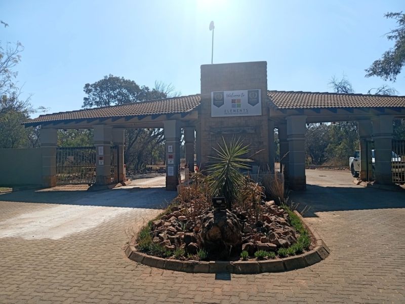 The main entrance gate and security access point for the Elements Private Golf Reserve, featuring stone masonry and paved driveway.