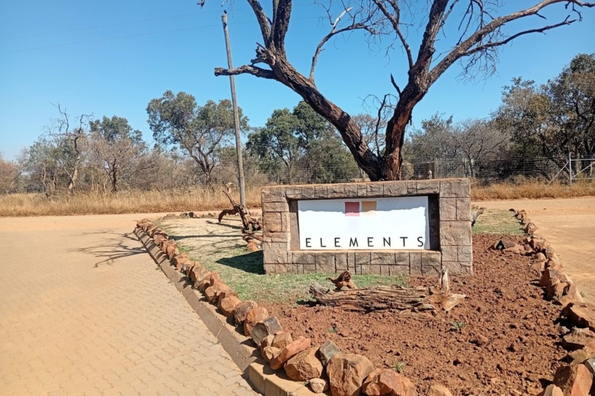Entrance signage for Elements estate featuring stone masonry, paved driveway access, and established landscaping in a natural bushveld setting.