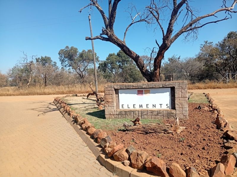 Entrance signage for Elements estate featuring stone masonry, paved driveway access, and established landscaping in a natural bushveld setting.