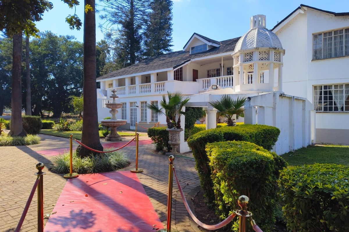 Rear view of the lodge featuring a paved walkway, stone fountain, and a distinctive cupola structure with a balcony overlooking the garden.