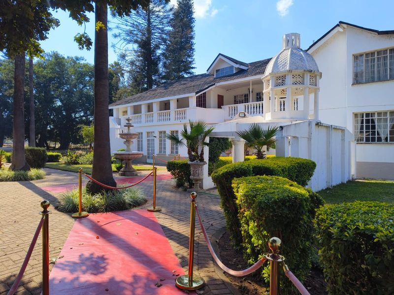 Rear view of the lodge featuring a paved walkway, stone fountain, and a distinctive cupola structure with a balcony overlooking the garden.