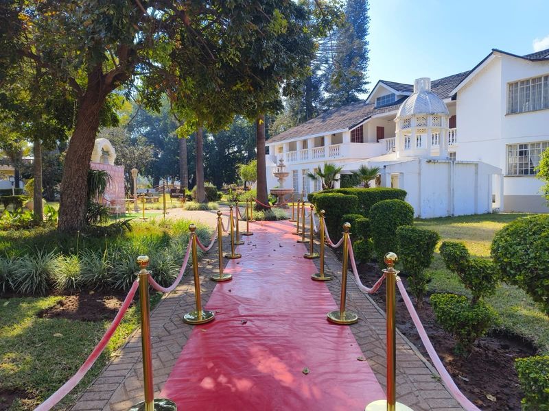 A well-maintained lodge exterior featuring a paved walkway, landscaped gardens, a decorative fountain, and a distinctive cupola architectural detail.